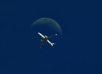 在飞行中的飞机，在月球的背景下，一般背景是深蓝色，极简主义
