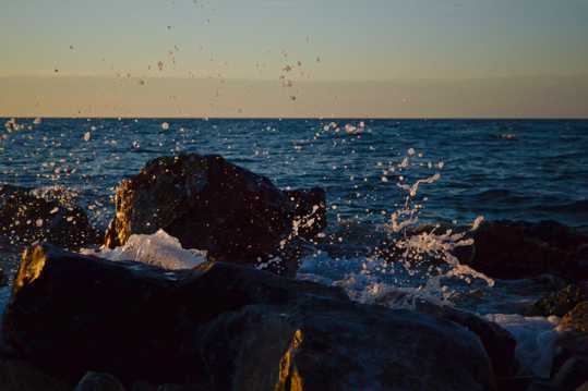 日落海潮击石图片